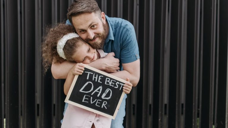 Father and daughter embrace with a sign saying 'The Best Dad Ever.'
